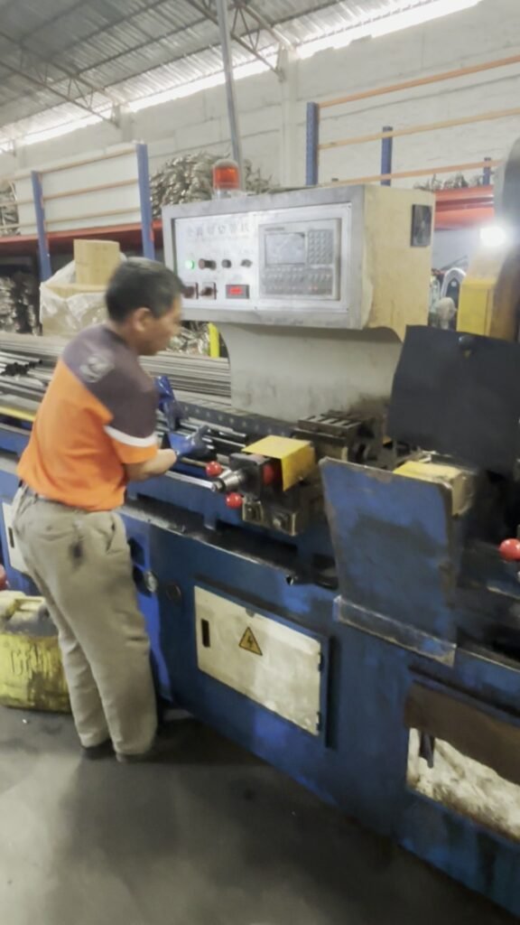 Worker operating a tube cutting machine for tubular motorcycle parts
