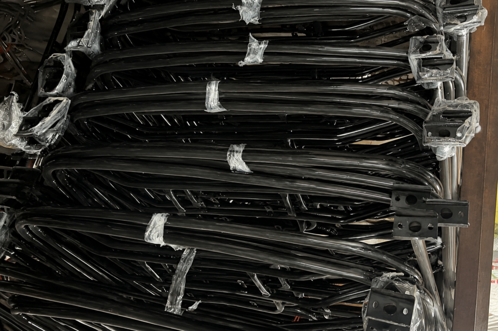 Finished black tubular motorcycle guards stacked with mounting brackets wrapped for protection